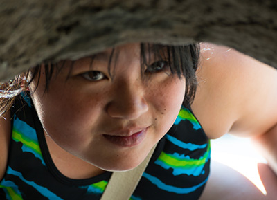 asian teen looking into a cave curiously